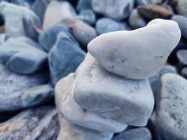 Stack of triangular stones.Group of white and colorful Stones.Pebble tower on the stones seaside.Stones pyramid on pebble beach symbolizing stability,zen,Rock,harmony,balance.Shallow depth of field. photo