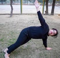 joven india practicando yoga al aire libre en un parque. hermosa chica practica pose básica de yoga. calma y relax, felicidad femenina. posturas básicas de yoga al aire libre foto