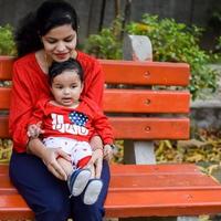 amoroso mamá que lleva de su bebé a sociedad parque. brillante retrato de contento mamá participación niño en su manos. madre abrazando su pequeño 9 9 meses antiguo hijo. foto