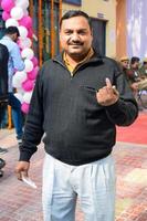 New Delhi, India - December 04 2022 - Unidentified people showing their ink-marked fingers after casting votes in front of polling booth of east Delhi area for MCD local body Elections 2022 photo