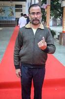 New Delhi, India - December 04 2022 - Unidentified people showing their ink-marked fingers after casting votes in front of polling booth of east Delhi area for MCD local body Elections 2022 photo