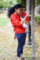 amoroso mamá que lleva de su bebé a sociedad parque. brillante retrato de contento mamá participación niño en su manos. madre abrazando su pequeño 9 9 meses antiguo hijo. foto