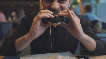 Man eats a hamburger in a cafe video