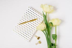 Flat lay Spring flowers Yellow tulips, cup of coffee white blank album notebook writing pen on white background. Lovely greeting card for March 8 Mothers day holiday birthday. Woman working desk photo