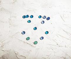 Small blue stones placed in the shape of a face. Blue dots in the shape of smiling face on textured white background. photo