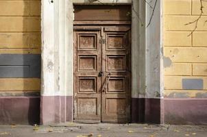 Abandoned old door with the lock. Rust on the metal lock. Peeling brown paint on the old door. photo