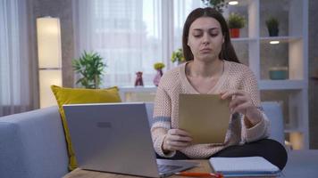 joven mujer sentado a hogar leyendo grave y importante papel y siendo conmocionado y frustrado. video