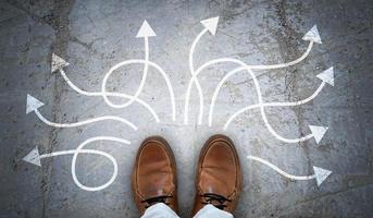 Brown Leather Shoes and Many Winding Chalky Arrows on Asphalt - Decision Concept photo