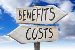 Costs, Benefits - Wooden Signpost with Two Arrows and Cloudy Sky in Background photo