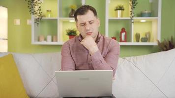 Mature man using laptop at home wants to come up with thoughtful and genius ideas. The man who does his work from the laptop at home does not come up with an idea and starts to think. video