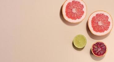 Sliced pieces of orange, lime and grapefruit on a beige background, top view photo