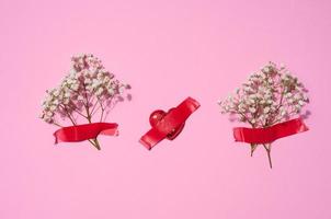 Bouquet of white gypsophila  and red textile hearts on a pink background, top view photo