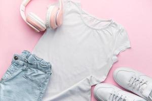 Child's t-shirt, shoes and headphones on pink backgrund photo