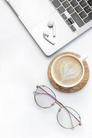 Modern white office desk table with laptop, notebook and other supplies. photo
