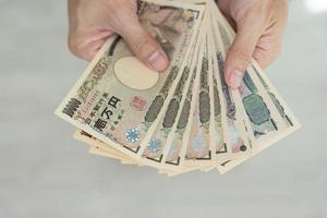 japonés yen dinero. cerca arriba de el japonés yen en mano. moneda de Japón ese es usado a cambiar, comprar, vender, acumular, invertir, financiero, intercambiar tasa, valor, contabilidad, internacional intercambiar foto