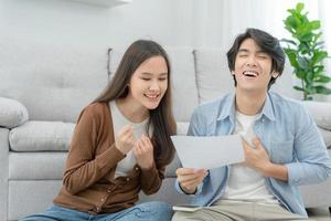 asian couple with happy and feel good finish and close large bills or invoices. close money to pay to expenses and credit card debt. shortage, mange financial problems, mortgage, refinancier, owner. photo