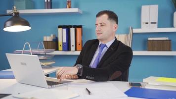 Confident successful businessman looking at camera and smiling. Businessman turns to camera while working on laptop, shows satisfaction and continues his work. video