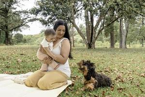 mamá jugando con bebé niña y perro en el parque. foto