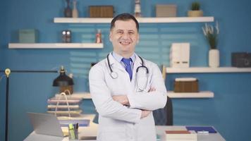 Confident positive male doctor smiling and reassuring camera. The doctor folds his arms, looking at the camera. The doctor smiles and shakes his head looking at the camera. video