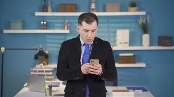 en företag man i en kostym mottar en meddelande på hans telefon i hans kontor och är Lycklig med de Bra Nyheter. video