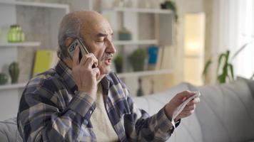 gammal man talande på de telefon handla om hög inkommande räkningen skuld. arg på de hög pris räkningen, de gammal man försöker till förklara hans problem till de nödvändig enheter på de telefon. video