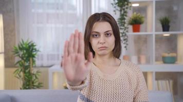 At home, young woman says stop with her hand against abuse and rape and looks at the camera without fear. Young woman making a stop sign with her hand against abuse and rape. video