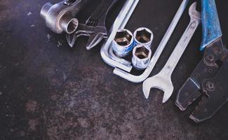 Hand tools consisting of wrenches, pliers, socket wrenches, laid out on old steel plate background. photo