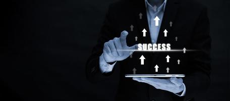 Businessman holding tablet and touch with word success with arrows  ,Business growth show arrows graph infographics on the black background, Success with arrow business, big data, copy space photo