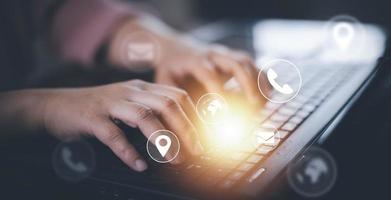 Communication and Contact us or Customer support hotline people connect. Hand using a laptop and touching on virtual screen contact icons, email and address, live chat with internet wifi. photo