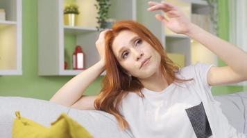 Young woman in anxious anticipation. Young woman sitting alone on sofa at home waiting sad and worried, thinking about her unhappiness, waiting for news. video