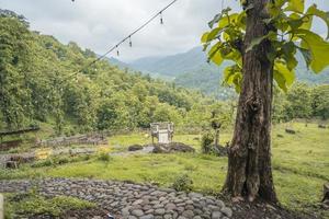 Scenic landscape of green hill view when cloudy sky after rain, Spring season East Java. The photo is suitable to use for nature background, holiday content social media and hill view poster.