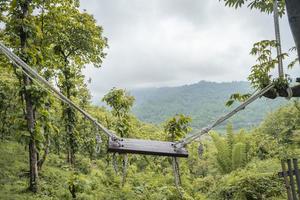 Landscape of empty swinging on the middle tropical forest with green hill view. The photo is suitable to use for nature background, holiday content social media and hill view poster.