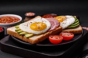 Delicious nutritious English breakfast with fried eggs, tomatoes and avocado photo