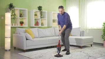 volwassen Mens vegen tapijt in modern leven kamer, schoonmaak met vacuüm schoner. een volwassen Mens reinigt de huis met een vacuüm schoner, beoefenen mooi zo hygiëne gewoonten naar in stand houden een schoon leven ruimte. video