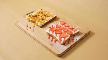 waffle with strawberry and cream on wood plate isolate on brown background photo