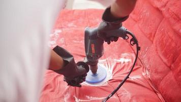 Worker polishing a red sofa with an electric grinder. photo