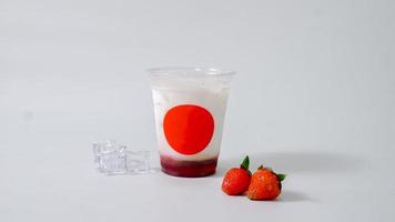 Strawberry drink in plastic cup with ice cubes on white background photo