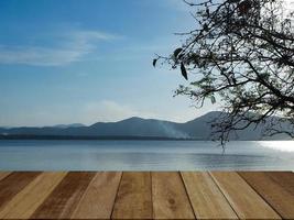 vacío antiguo de madera mesa y un ver de el reservorio atmósfera y montañas y cielo antecedentes. para presente tu productos foto