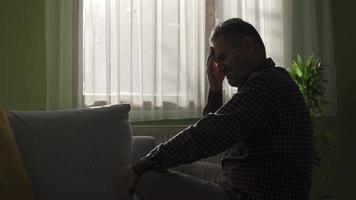 Unhappy and depressed middle-aged man crying alone at home by the window. Thoughtful mature man looking away from window, feeling sad, thoughtful melancholy, crying. video