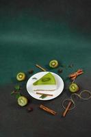 Cheesecake with Kiwi, cinnamon stick and leaves mint on a green background. Copy cpase for text photo