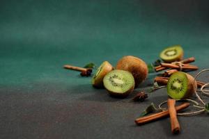 Slices of fresh, juicy Kiwi on a Green background. Decorated with cinnamon sticks, badyan, mint leaves. Fruity decorated background photo