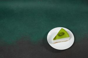 rebanada de tarta de queso con kiwi, canela palo y hojas menta en un verde antecedentes. Copiar cpase para texto foto