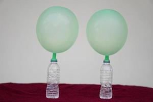 Green inflated balloons on top of transparent test bottles. Concept, science experiment about reaction of chemical substance, vinegar and baking soda that cause balloon inflat. Last step of experiment photo