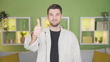 content Jeune homme à la recherche à caméra en disant toi' et souriant tandis que donnant positif signe. content Jeune homme montrer du doigt à caméra, souriant et donnant une positif signe avec mains. video