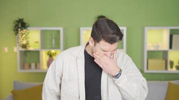 The young man suddenly starts to sneeze due to dust and allergies. The man who started sneezing because of the dust in the room, because of his allergies. video