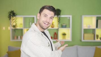 el joven hombre diciendo alguna cosa hacia el cámara señales él a venir. contento linda joven hombre sonriente hacia cámara haciendo ven signo. video