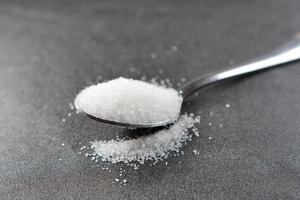 white sugar on a silver spoon on table photo