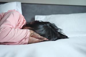 a upset child girl cover her face with hand on bed photo