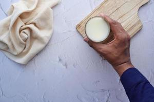 man hand holding glass of milk at early morning photo