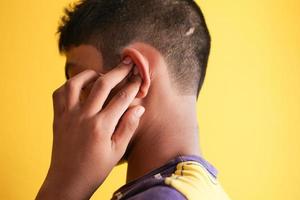 teenage boy having ear pain touching his painful ear , photo